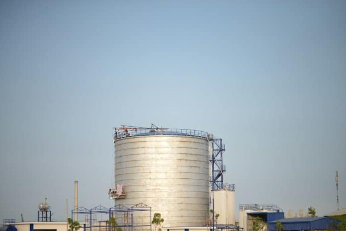 a large white water tank sitting on top of a lush green field